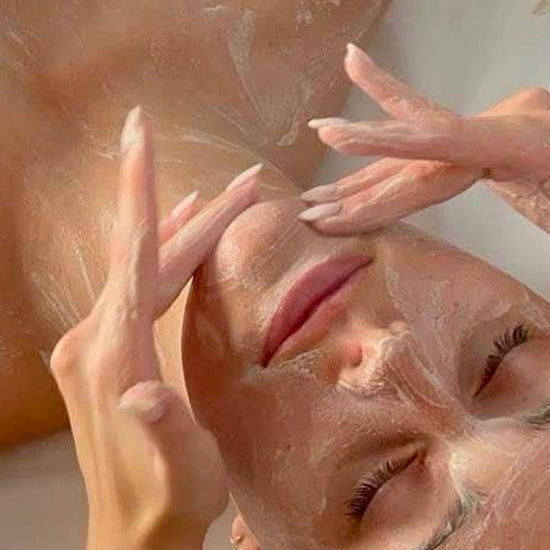 Person applying a facial mask with their hands