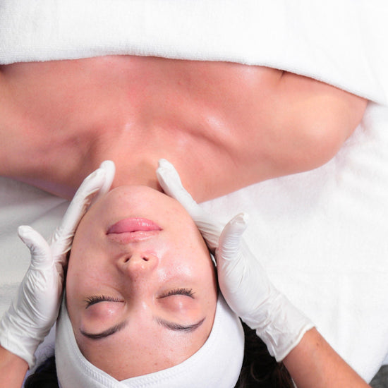 Person receiving a facial treatment with white gloves and towels.