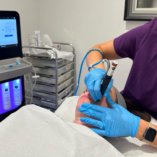 Person receiving a medical procedure with a technician applying equipment to their head.