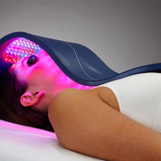 Person receiving LED light therapy on a gray background
