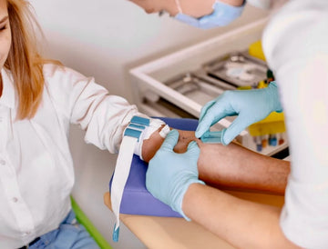 Person getting a blood sample from a healthcare professional in a medical setting - Ageless Medical Clinic