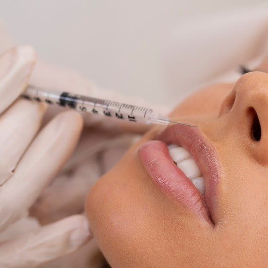 Person receiving a facial injection with a syringe held by gloved hands.