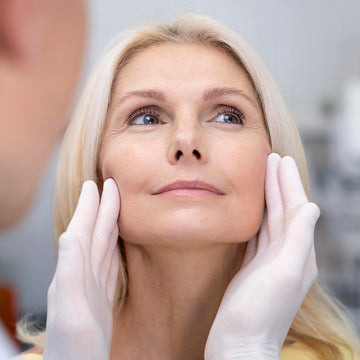 Woman receiving facial treatment with gloved hands, blurred background