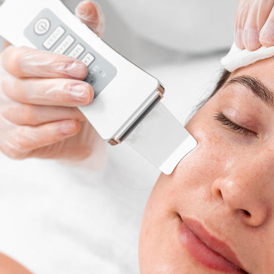 Person receiving a facial treatment with a device on a neutral background
