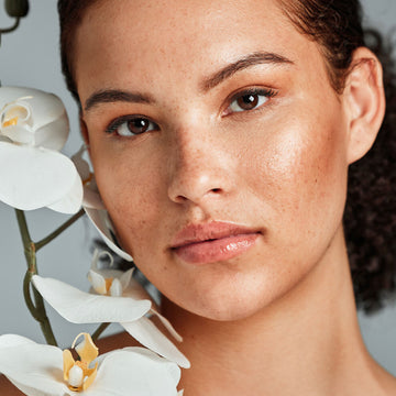 Close-up of a woman's face with white flowers in the foreground