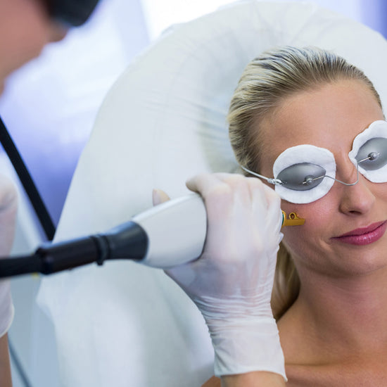 Woman receiving laser treatment with protective goggles on a medical setting.