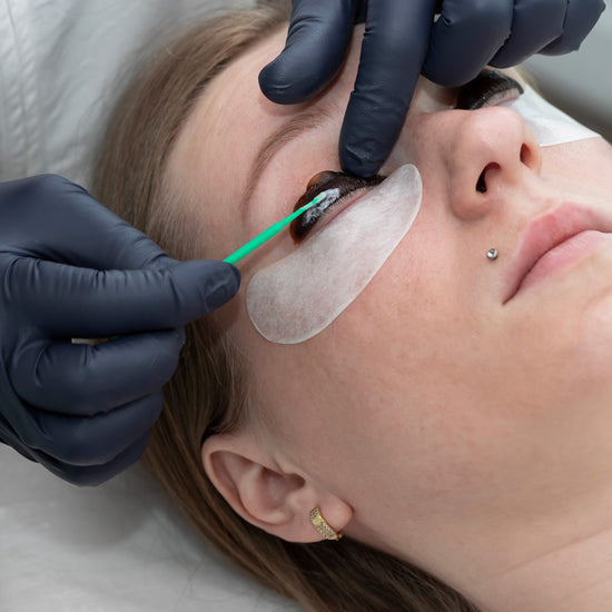 Person receiving an eye examination with a green tool, wearing gloves.