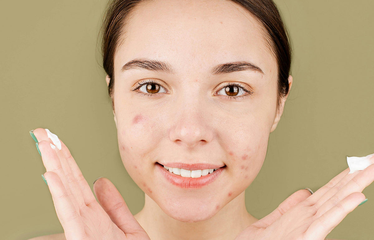 Woman applying cream to her face with a green background
