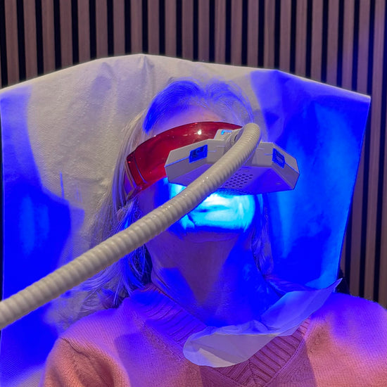 Person wearing a LED face mask with blue light in a room.